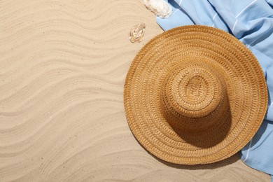 Photo of Beach towel, straw hat and seashells on sand outdoors, flat lay. Space for text