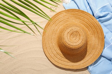 Photo of Beach towel, straw hat and seashell on sand outdoors, flat lay. Space for text