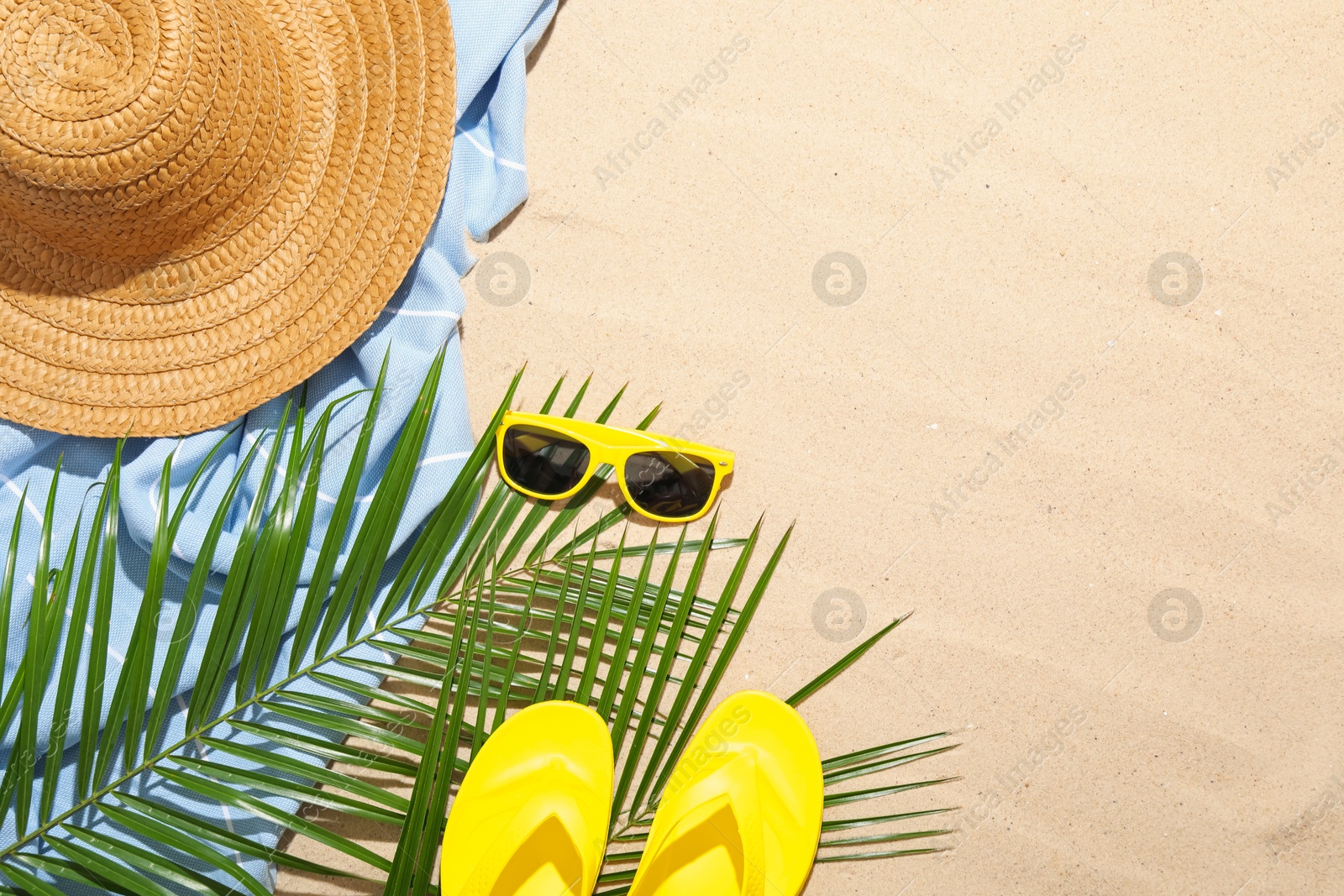 Beach towel, straw hat, sunglasses, flip flops and palm leaves on sand outdoors, flat lay. Space for text Photo of Beach towel, straw hat, sunglasses, flip flops and palm leaves on sand outdoors, flat lay. Space for text