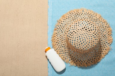 Photo of Beach towel, straw hat and sunscreen product on sand outdoors, flat lay. Space for text