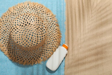 Photo of Beach towel, straw hat and sunscreen product on sand outdoors, flat lay. Space for text