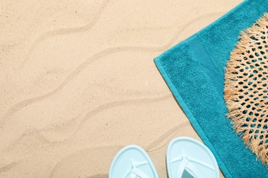Photo of Beach towel, flip flops and straw hat on sand outdoors, flat lay. Space for text