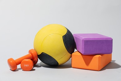 Photo of Medicine ball, dumbbells and foam blocks on light grey background