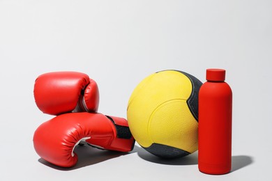 Photo of Medicine ball, boxing gloves and water bottle on light grey background