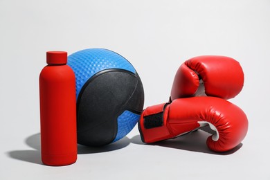 Photo of Medicine ball, boxing gloves and water bottle on light grey background