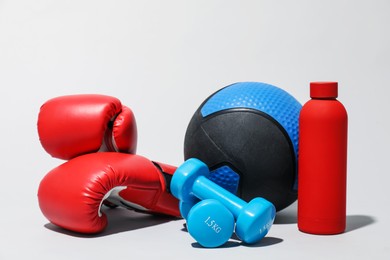 Photo of Medicine ball, boxing gloves, dumbbells and water bottle on light grey background