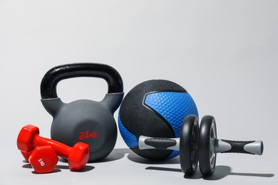 Photo of Medicine ball, ab wheel, kettlebell and dumbbells on light grey background