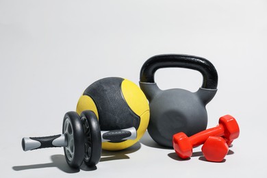 Photo of Medicine ball, ab wheel, kettlebell and dumbbells on light grey background