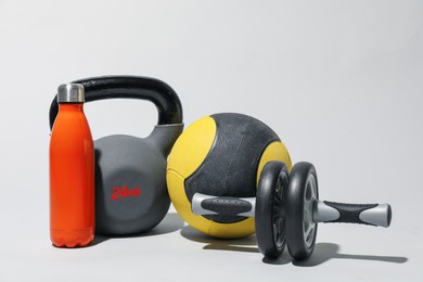 Photo of Medicine ball, ab wheel, kettlebell and water bottle on light grey background