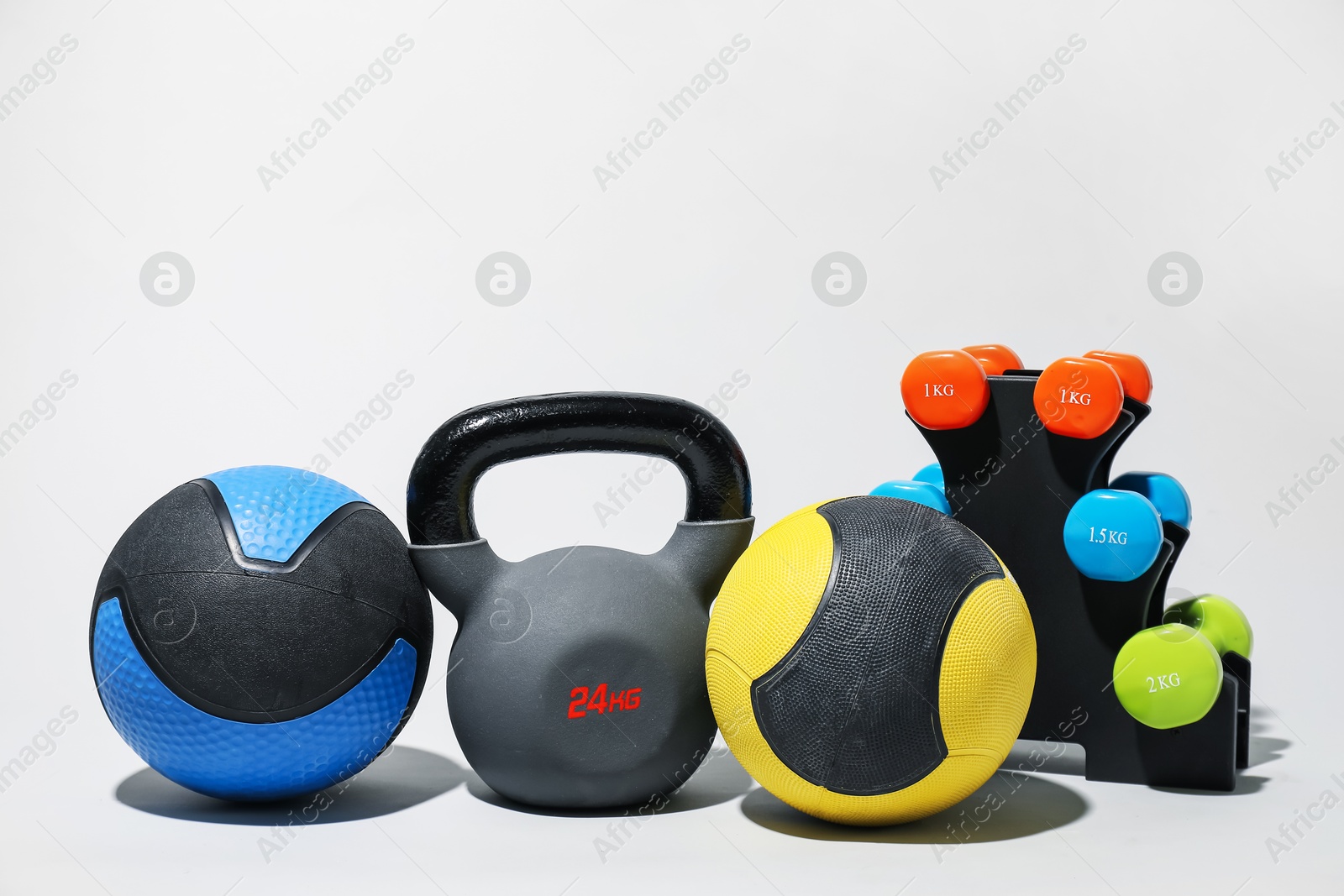 Medicine balls, kettlebell and dumbbells on light grey background Photo of Medicine balls, kettlebell and dumbbells on light grey background