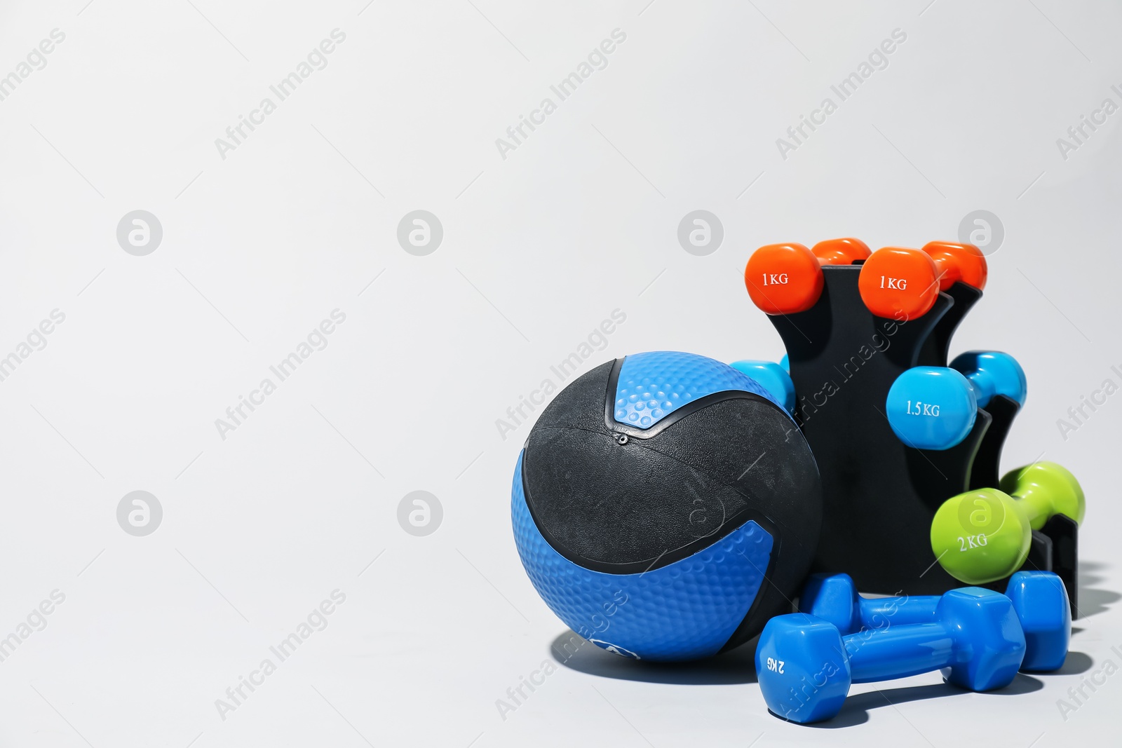 Medicine ball and dumbbells on light grey background, space for text Photo of Medicine ball and dumbbells on light grey background, space for text