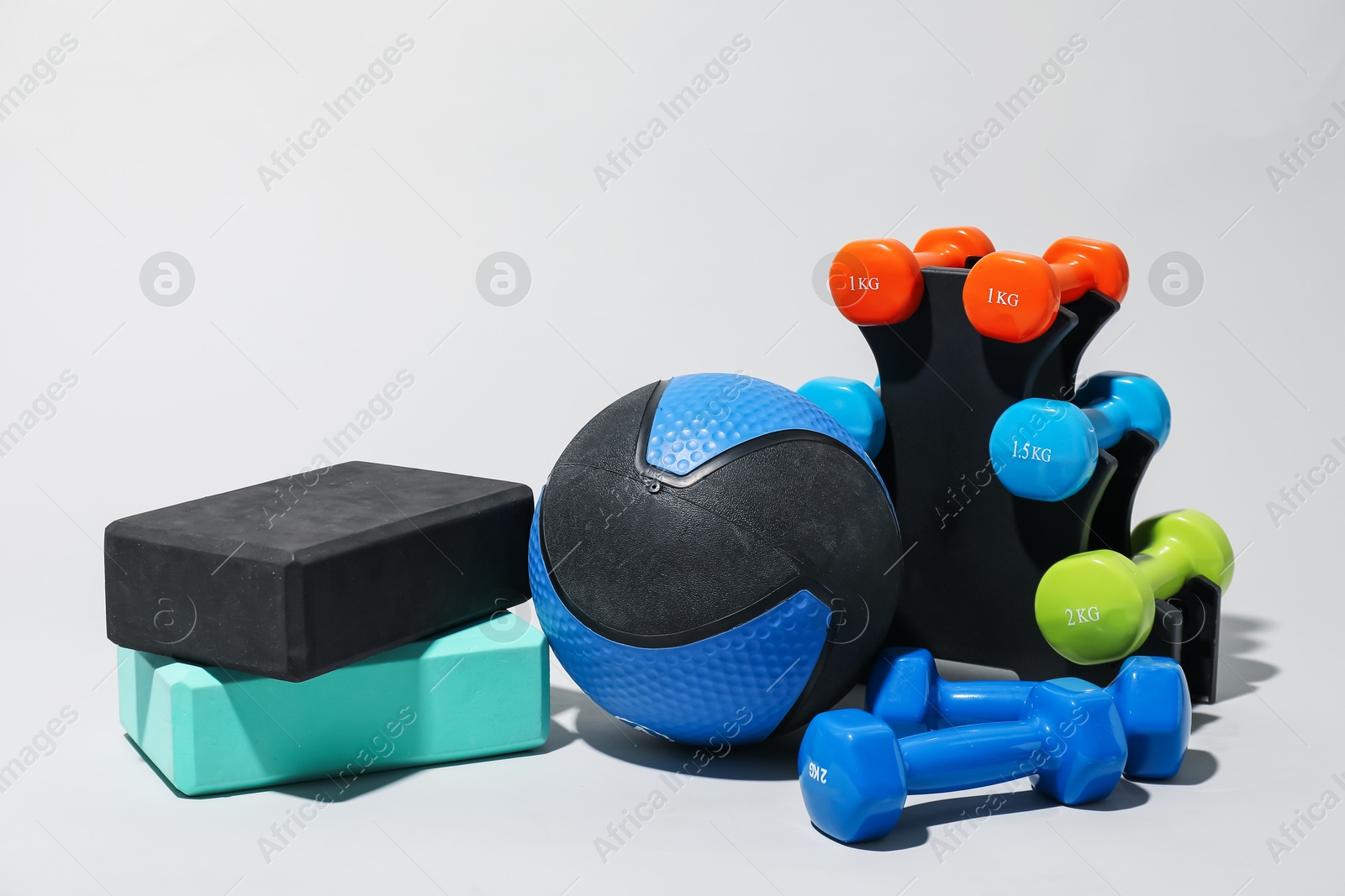 Medicine ball, dumbbells and foam blocks on light grey background Photo of Medicine ball, dumbbells and foam blocks on light grey background