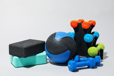 Photo of Medicine ball, dumbbells and foam blocks on light grey background