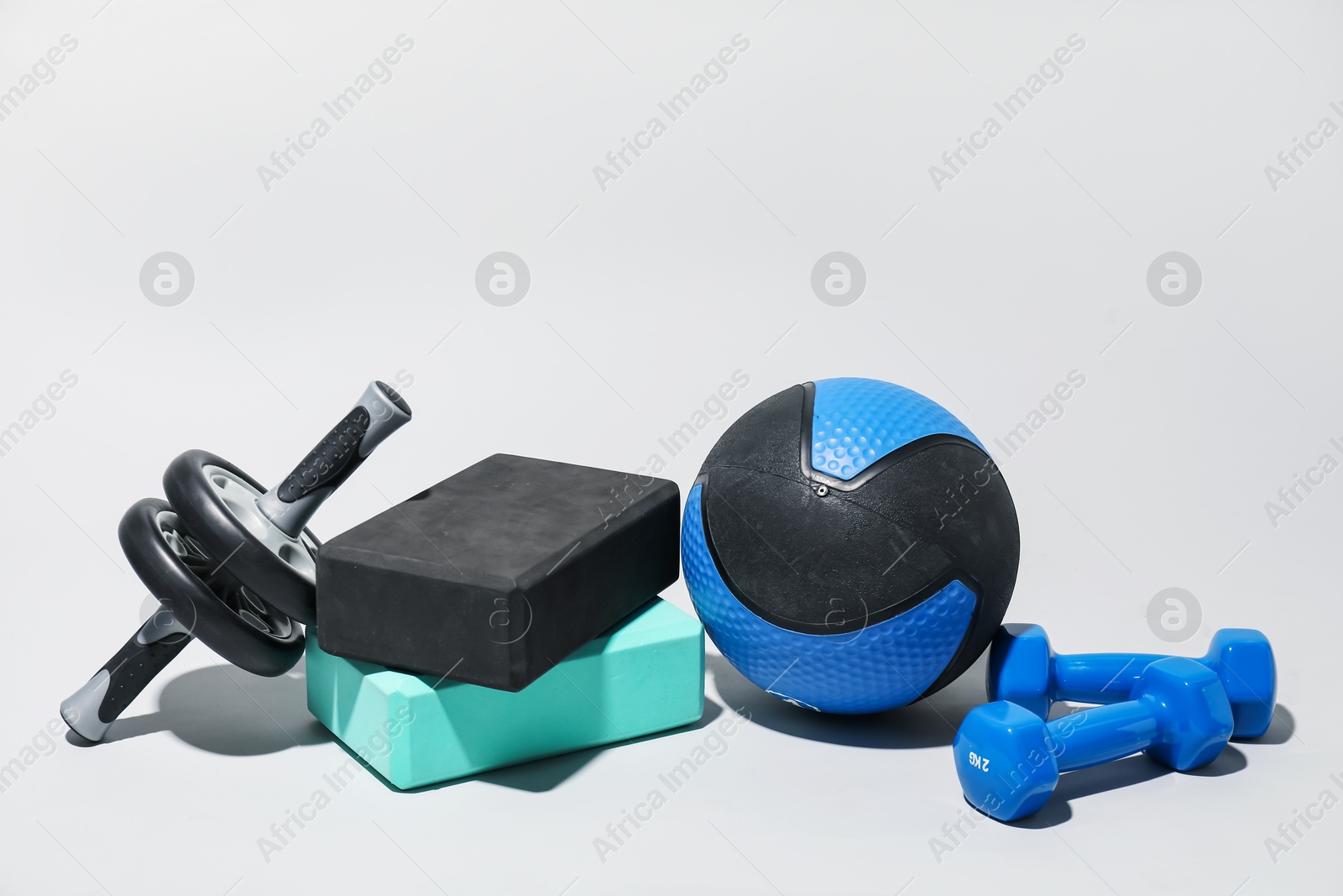 Medicine ball, dumbbells, ab wheel and foam blocks on light grey background Photo of Medicine ball, dumbbells, ab wheel and foam blocks on light grey background
