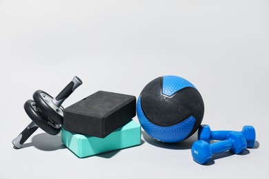 Photo of Medicine ball, dumbbells, ab wheel and foam blocks on light grey background