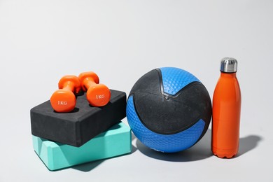 Photo of Medicine ball, dumbbells, water bottle and foam blocks on light grey background