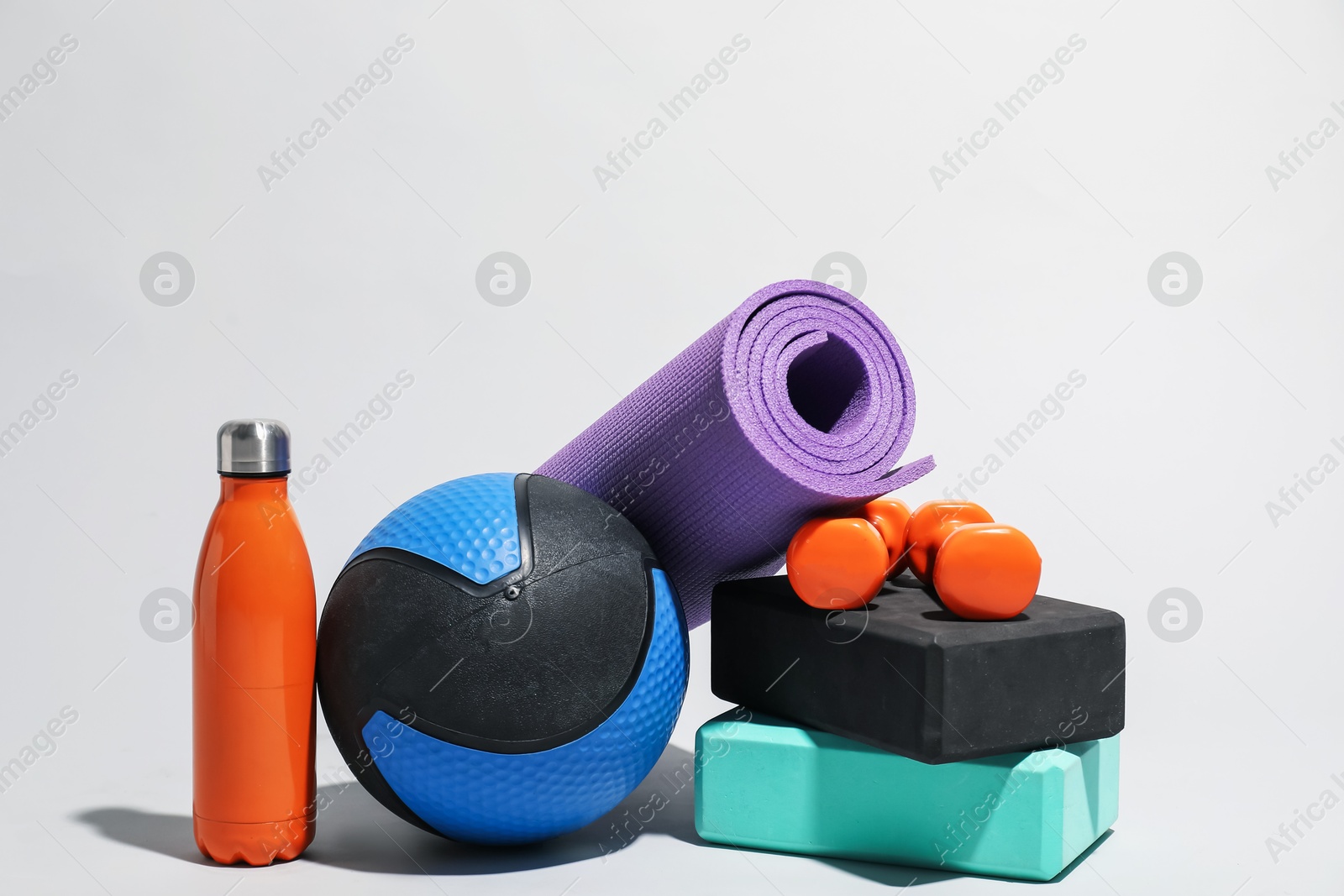 Medicine ball, dumbbells, water bottle, foam blocks and fitness mat on light grey background Photo of Medicine ball, dumbbells, water bottle, foam blocks and fitness mat on light grey background