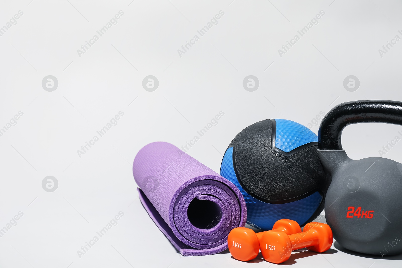 Medicine ball, dumbbells, kettlebell and fitness mat on light grey background. Space for text Photo of Medicine ball, dumbbells, kettlebell and fitness mat on light grey background. Space for text