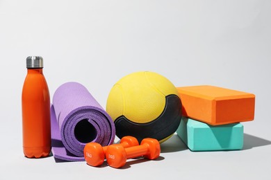 Photo of Medicine ball, dumbbells, foam blocks, water bottle and fitness mat on light grey background