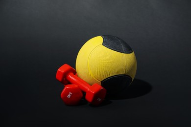 Photo of Medicine ball and dumbbells on black background