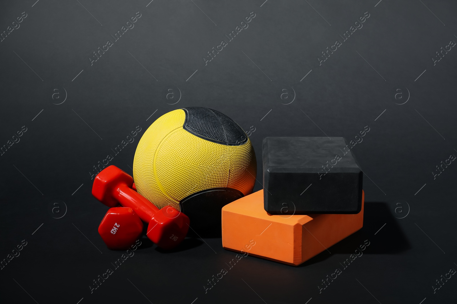 Medicine ball, dumbbells and foam blocks on black background Photo of Medicine ball, dumbbells and foam blocks on black background