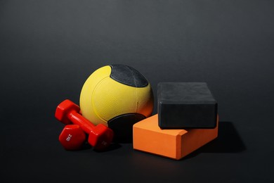Photo of Medicine ball, dumbbells and foam blocks on black background