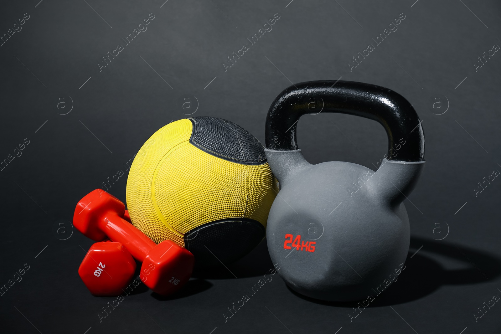 Medicine ball, dumbbells and kettlebell on black background Photo of Medicine ball, dumbbells and kettlebell on black background