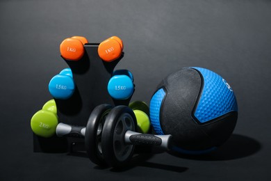 Photo of Medicine ball, dumbbells and ab wheel on black background