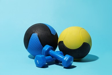 Photo of Medicine balls and dumbbells on light blue background