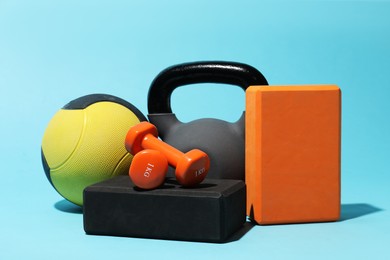 Photo of Medicine ball, kettlebell, foam blocks and dumbbells on light blue background
