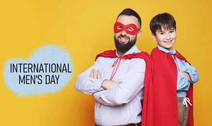 Image of International Men's Day card. Happy man and his son dressed as superheroes against orange background