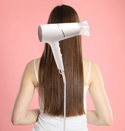 Image of Photo of woman divided by hair dryer showing before and after hair styling, pink background
