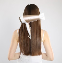 Image of Before and after hair styling. Photo of woman divided by hair dryer against grey background