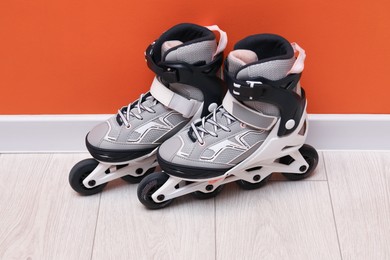 Photo of Pair of roller skates on floor near orange wall
