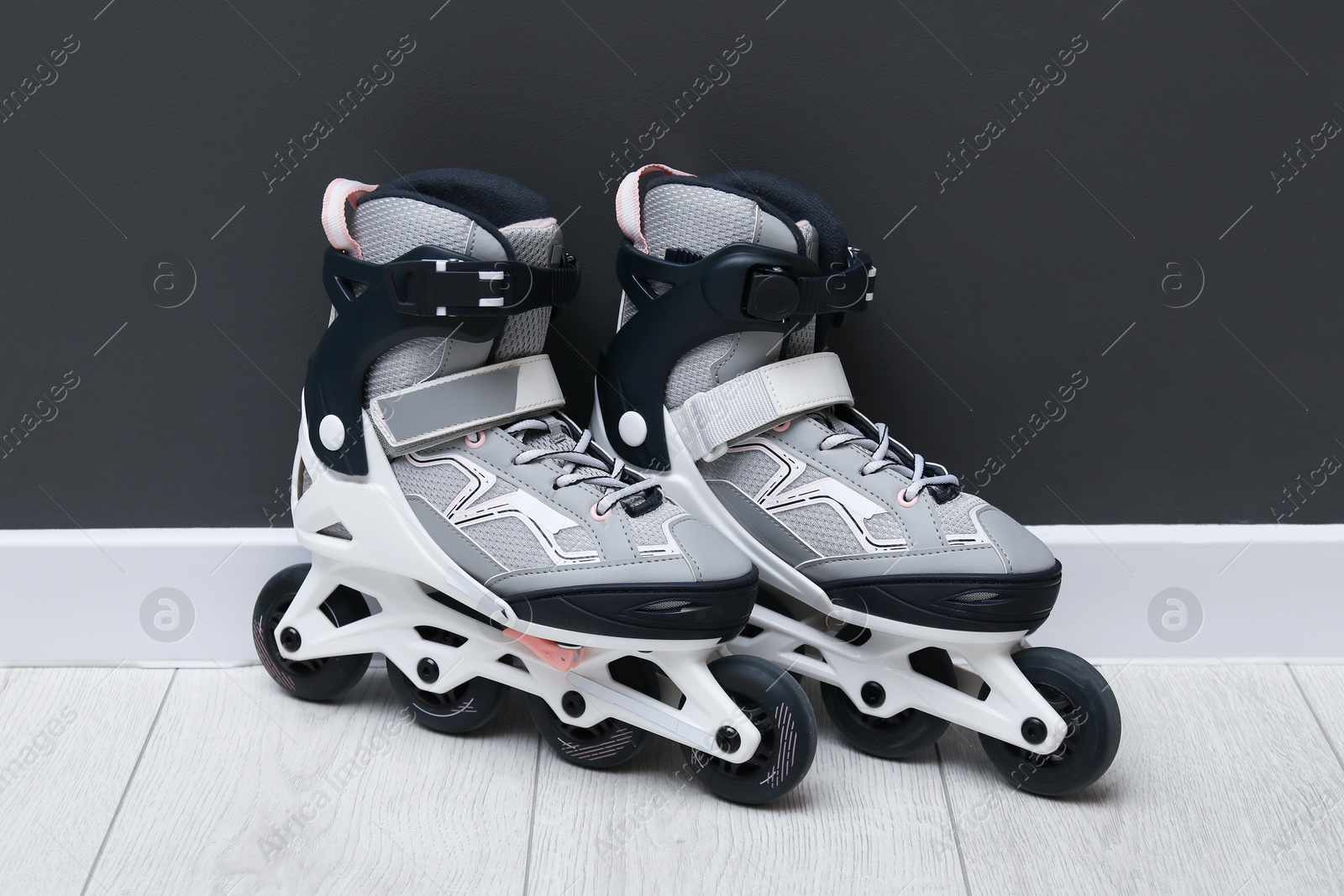 Pair of roller skates on floor near black wall Photo of Pair of roller skates on floor near black wall