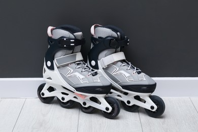Photo of Pair of roller skates on floor near black wall