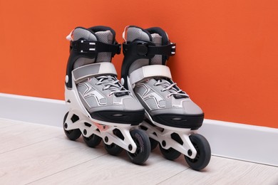 Photo of Pair of roller skates on floor near orange wall