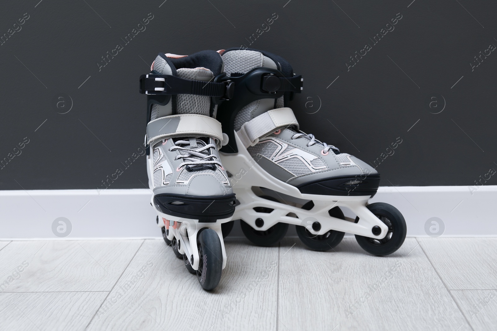 Pair of roller skates on floor near black wall Photo of Pair of roller skates on floor near black wall
