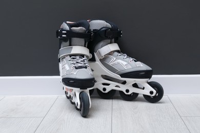 Photo of Pair of roller skates on floor near black wall