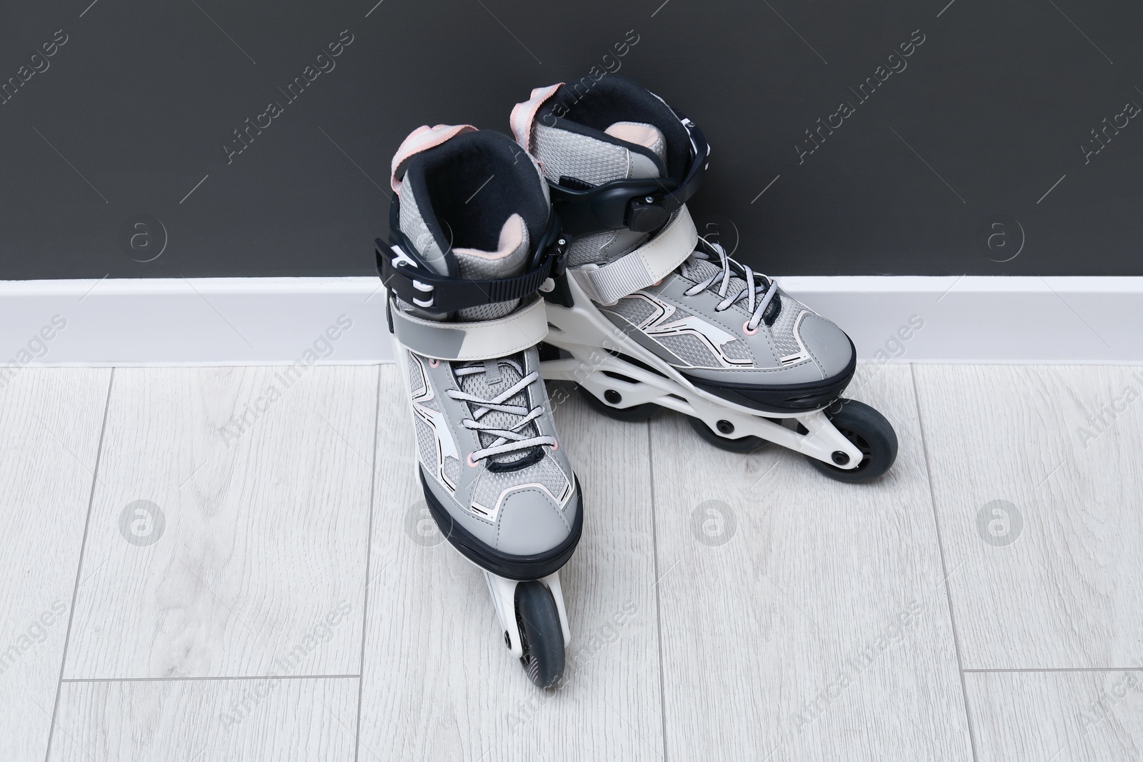 Pair of roller skates on floor near black wall Photo of Pair of roller skates on floor near black wall
