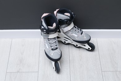 Photo of Pair of roller skates on floor near black wall