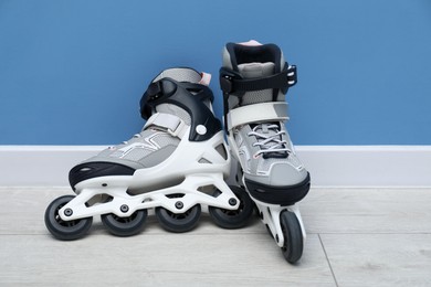 Photo of Pair of roller skates on floor near light blue wall