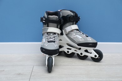 Photo of Pair of roller skates on floor near light blue wall