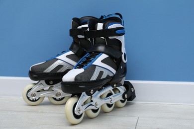Photo of Pair of roller skates on floor near light blue wall