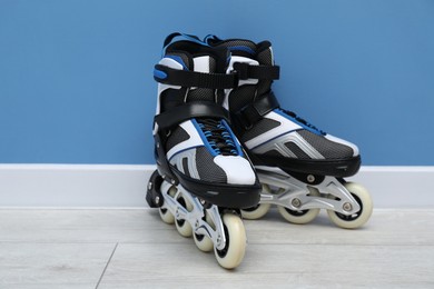 Photo of Pair of roller skates on floor near light blue wall