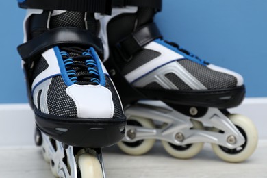 Photo of Pair of roller skates on floor near light blue wall, closeup