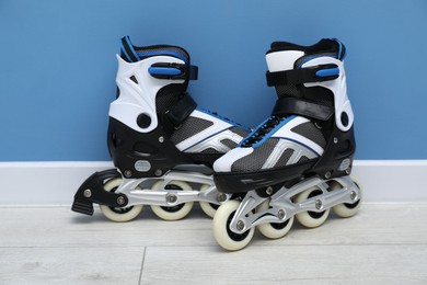 Photo of Pairs of roller skates on floor near light blue wall
