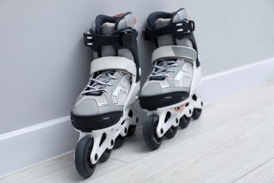 Photo of Pair of roller skates on floor near white wall