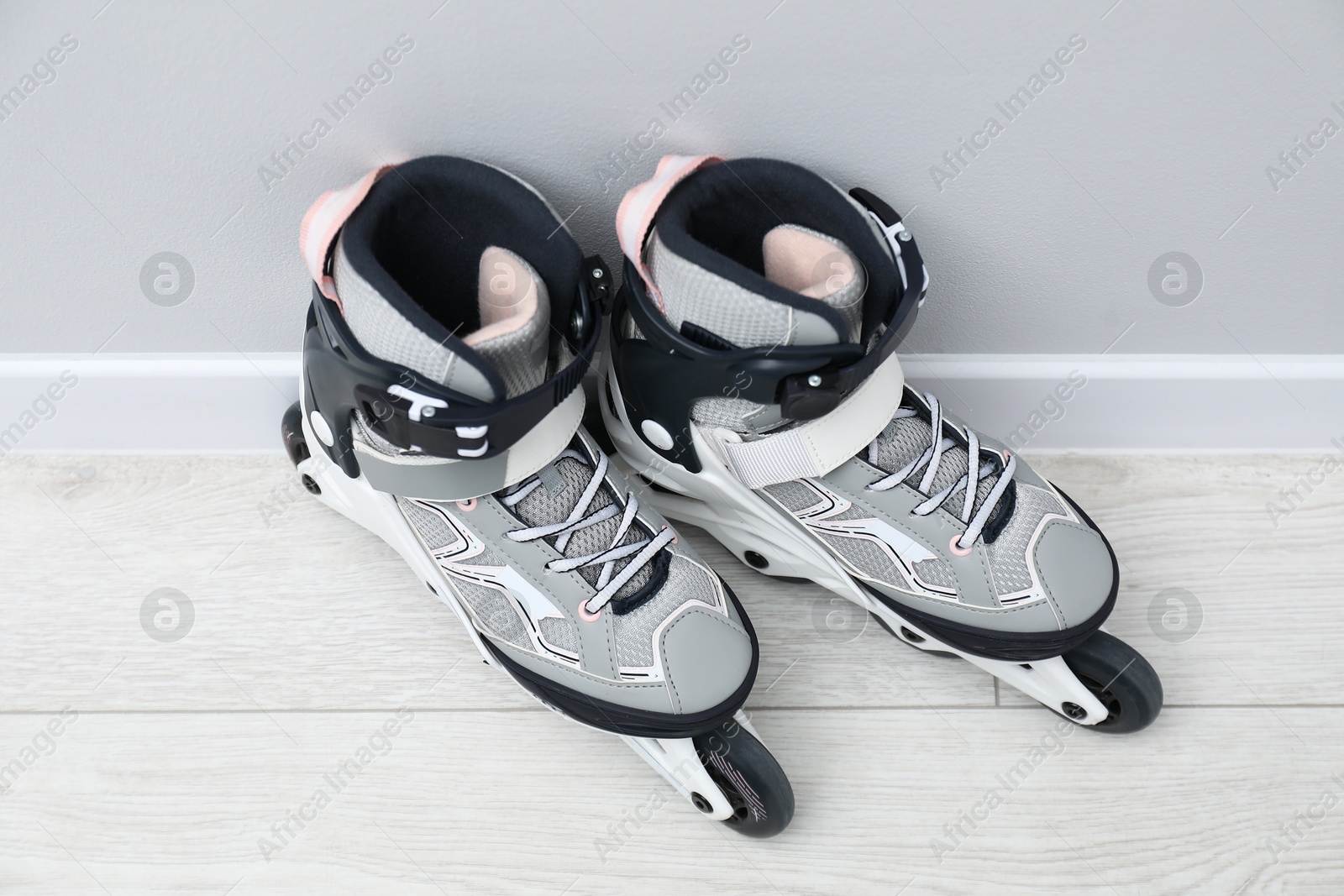 Pair of roller skates on floor near white wall Photo of Pair of roller skates on floor near white wall