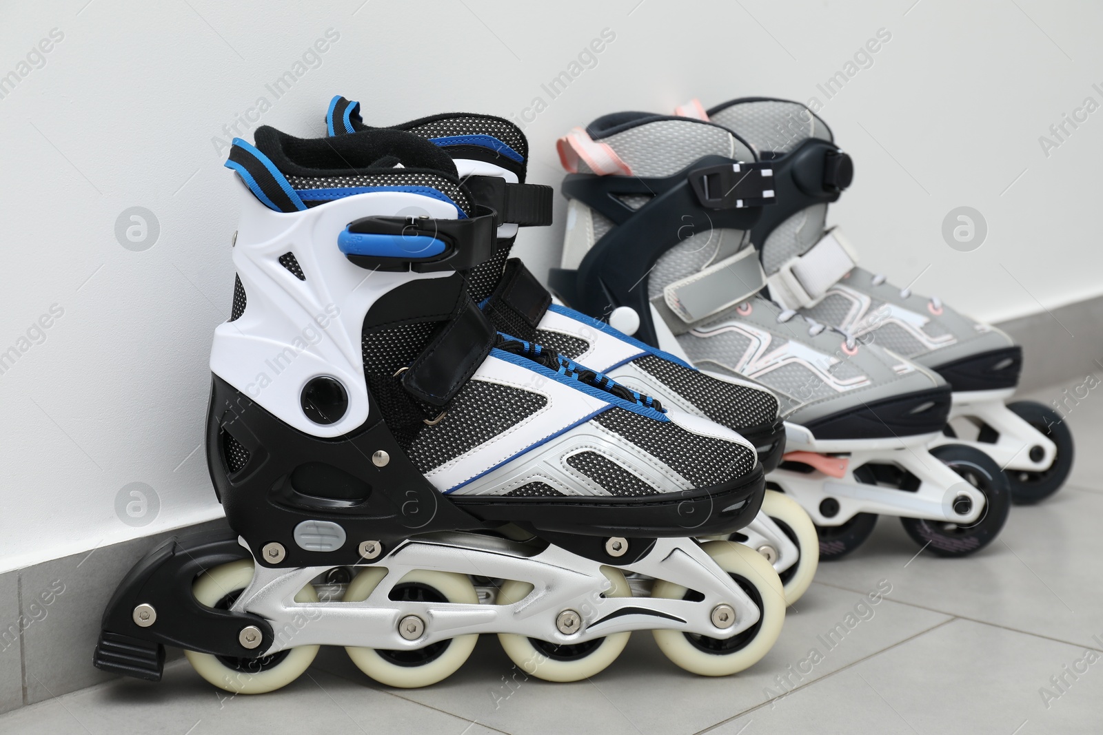 Pairs of roller skates on floor near white wall Photo of Pairs of roller skates on floor near white wall